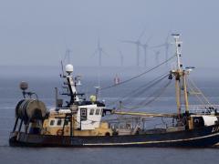 Vissersboot op zee met op de achtergrond windturbines